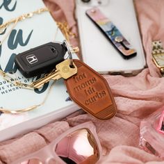 the keychain is next to some sunglasses and a cell phone on a pink blanket