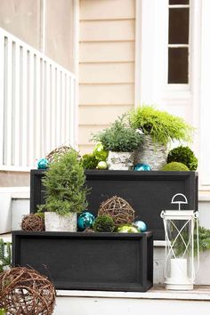 two black boxes filled with plants and ornaments on the front steps in front of a house