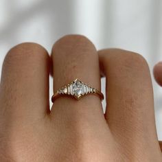 a woman's hand with a diamond ring on top of her finger, showing the side stones