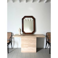 a wooden table with a mirror on top of it next to two chairs and a vase