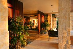 an outdoor living area with large plants and stone walls, along with a wooden bench in the foreground