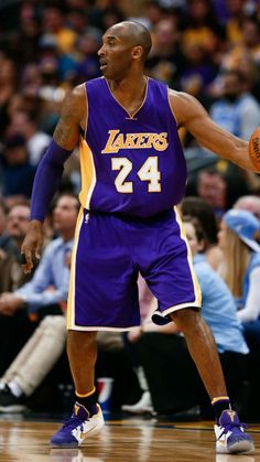 a basketball player dribbling the ball in front of an audience at a game