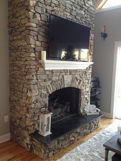 a stone fireplace with a flat screen tv mounted on it's mantle in a living room