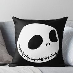 a black and white pillow with a jack skellingy face on the front throw pillow