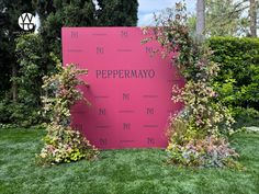 a pink sign that says pepermayo in front of some bushes and trees