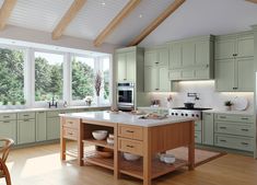 a large kitchen with green cabinets and white counter tops, along with wooden flooring