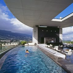 a person swimming in a large pool next to a tall building with a bar on top