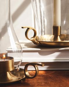 a candle sits on top of a stack of books next to some glass vases