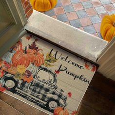 a welcome pumpkin door mat with an old truck and pumpkins on the front porch