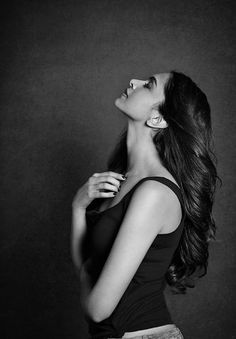 a black and white photo of a woman with her hair blowing in the wind looking up