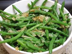 a white bowl filled with green beans on top of a counter