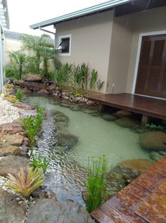 a small pond in front of a house with wooden steps leading up to the door