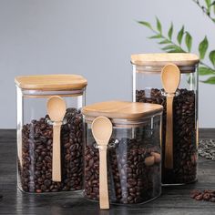 three glass containers with wooden spoons and coffee beans