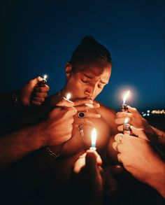 two men lighting candles in the dark with one man's shirt open and his hands holding lighters