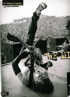 a man laying on the ground with a guitar in his hand and an advertisement above him