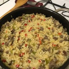 a skillet filled with rice and meat on top of a stove next to utensils