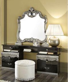 a large mirror sitting on top of a wooden table next to a white ottoman and lamp