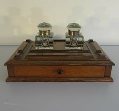 an antique wooden box with two silver cups on it's top and one in the middle