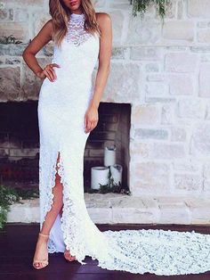 a woman standing in front of a fireplace wearing a white dress with high slits