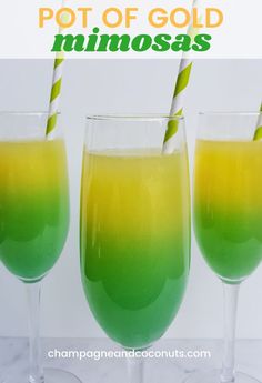 two glasses filled with green and yellow liquid next to each other on a white table