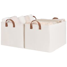 two white storage baskets with brown handles on the sides and one is filled with blankets