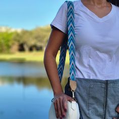 a woman wearing a white t - shirt and blue braided necktie holding a white purse