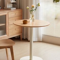 a small table with flowers on it in front of a window