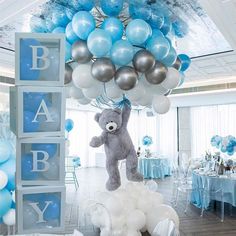 a teddy bear is suspended from a bunch of balloons in the middle of a room