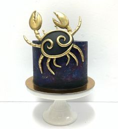 a blue cake with gold crab decorations on it's top and bottom tiers