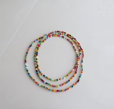 "This Multicolor bead necklace is made with Japanese seed beads of colors: white, blue, turquoise, and green. It can wear alone or layered with other necklaces for a Bohemian style. You can just wrap around your arm and go. Bracelet wraps around approx. 5-6 times This listing is for ONE necklace. Three color versions of the necklace are available. Primary photo shows the necklace version 1. DETAILS - Japanese glass seed beads 4 mm - Quality strong nylon string - Necklace length. Choose in the dr Summer Multi-strand Colorful Beaded Necklaces, Multicolor Spacer Beads Jewelry For Summer, Multi-strand Beaded Necklaces For Summer, Summer Multicolor Jewelry With Spacer Beads, Multicolor Beaded Jewelry For Beach, Colorful Beaded Long Necklace For Beach, Festival Jewelry With 108 Heishi Beads, Adjustable Long Beaded Necklace For Summer, Multicolor Long Necklace For Summer