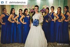 a group of women standing next to each other wearing blue dresses and holding bouquets