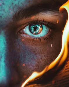 a man's face with fire painted on it and blue eyes looking at the camera