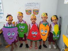 several children are holding up paper cutouts in the shape of fruit and vegetable characters