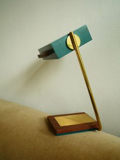 a desk lamp sitting on top of a table next to a wooden block with a metal base