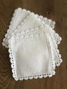 four white linen napkins with scalloped edges on a wooden table, top view