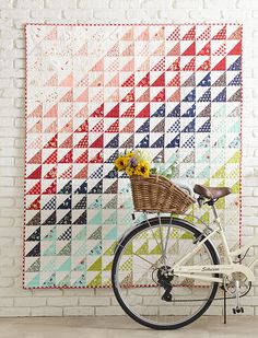 a bicycle parked next to a wall with a quilt on it