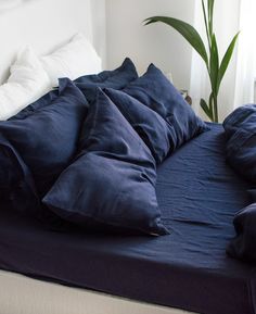 an unmade bed with blue sheets and pillows