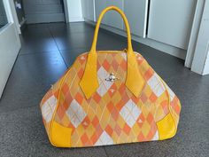 Incredible Vivienne Westwood Argyle Derby Bag in amazing yellow/tangerine colourway. Fantastic unworn condition. No dust bag.  41 cms length 29 cms height  18 cms depth Designer Yellow Bag With Top Carry Handle, Designer Yellow Satchel For Travel, Designer Orange Satchel For Travel, Designer Yellow Satchel With Handles, Grease Style, Resort 2024, Vintage Evening Bags, Top Handle Bags, Purse Accessories