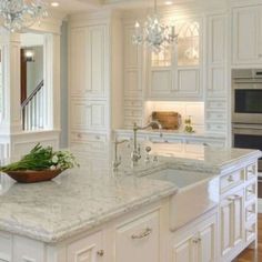 a large kitchen with white cabinets and marble counter tops