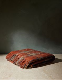 an orange and blue plaid blanket sitting on top of a table next to a vase