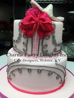 a three tiered cake decorated with pink and silver icing, bows and seashells