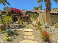 a home with landscaping and palm trees in the front yard, including rocks and plants