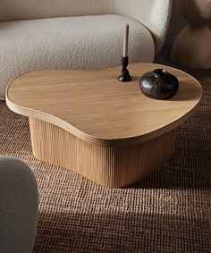 a wooden table sitting on top of a rug next to a white couch and chair