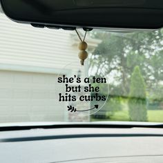 a car windshield with a sign that says she's a ten but she hits curbs