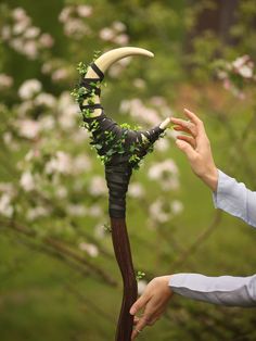 a woman holding an odd looking hat with horns and vines on it's head