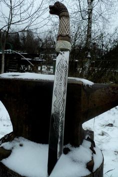 a large metal object sitting on top of snow covered ground next to some trees and bushes