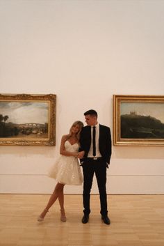 a man and woman standing next to each other in an art gallery