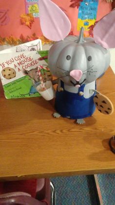 a mouse figurine is sitting on a table next to a book and some cookies