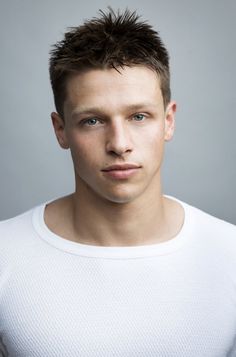 a young man is posing for a photo with his hair in the air and wearing a white t - shirt