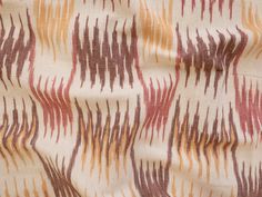 an orange, red and brown pattern is on a white fabric with small lines in the center